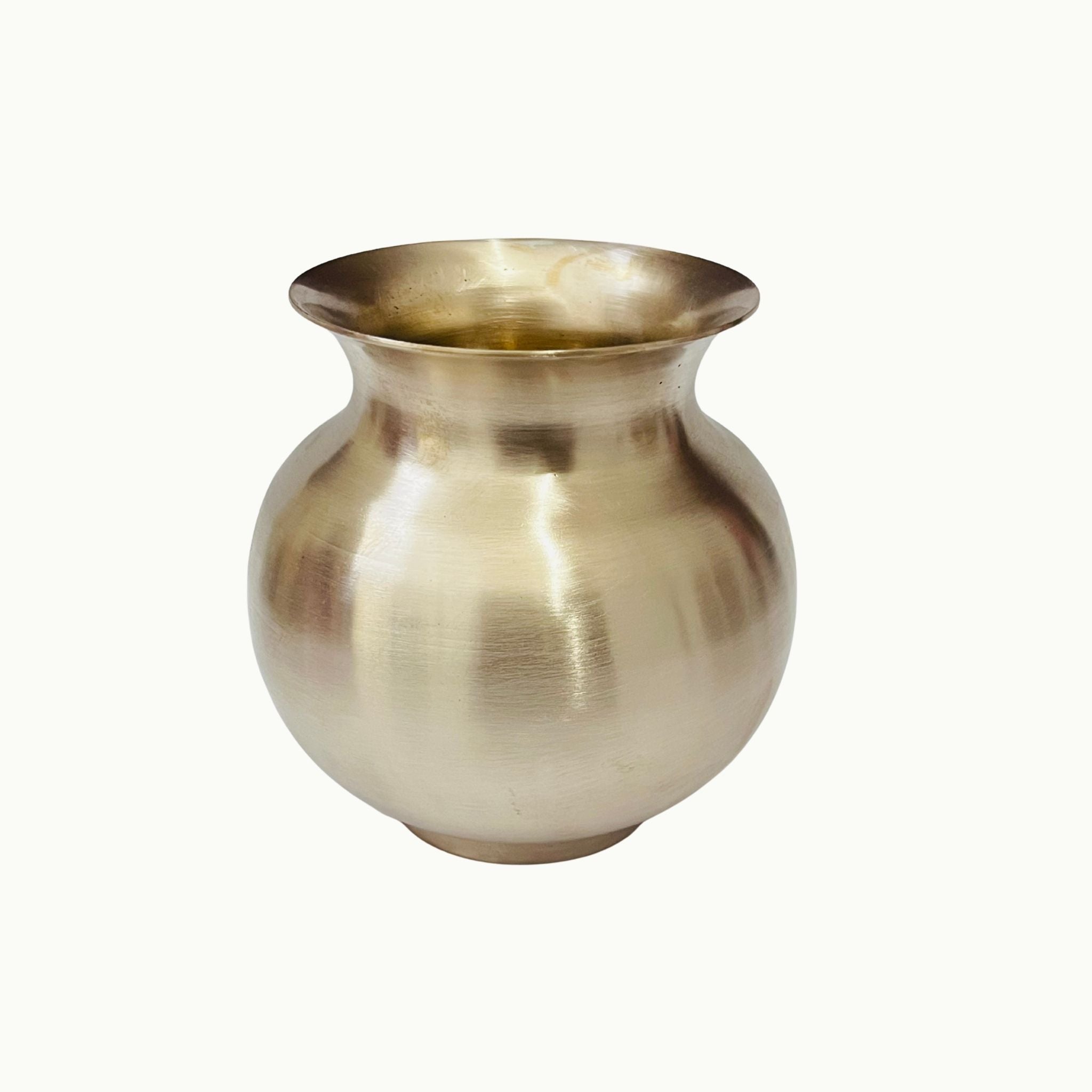 A small metallic brass pot with a rounded body and flared rim, photographed against a plain off-white background.