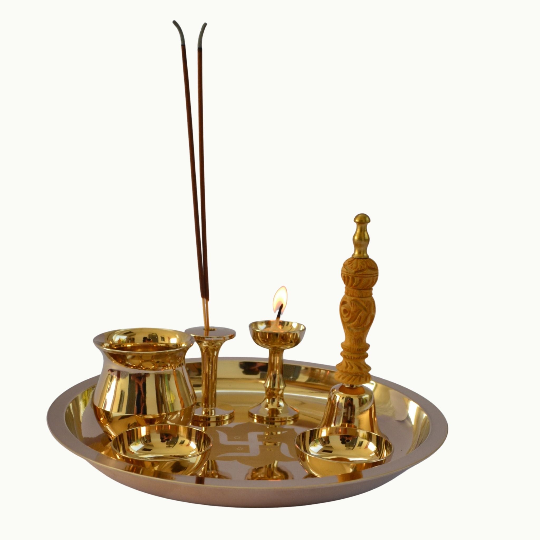 A polished brass ritual tray set containing a brass incense holder with two incense sticks, a brass oil lamp with a lit flame, a small brass bowl, a brass dish, and a carved brass stand, all arranged on a plain white background.